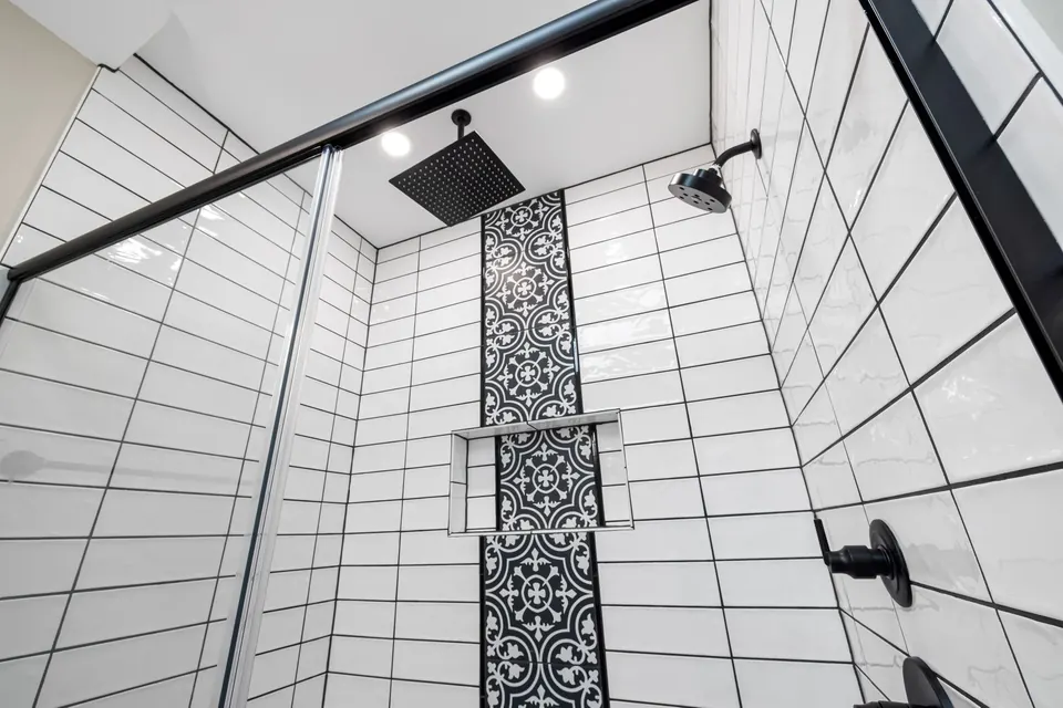 Douche carrelée avec une bande de carreaux à motifs et une robinetterie noire