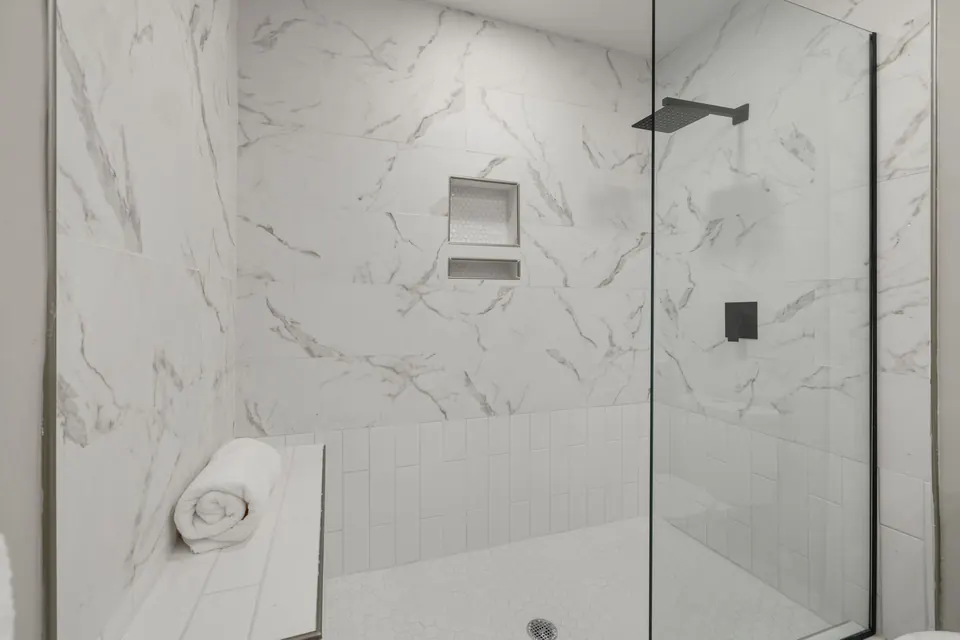 Douche de plain-pied en carrelage effet marbre blanc, paroi vitrée et banc