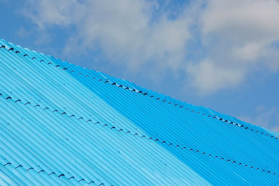 Toiture en tôle ondulée bleue vue en contre-plongée sous un ciel clair